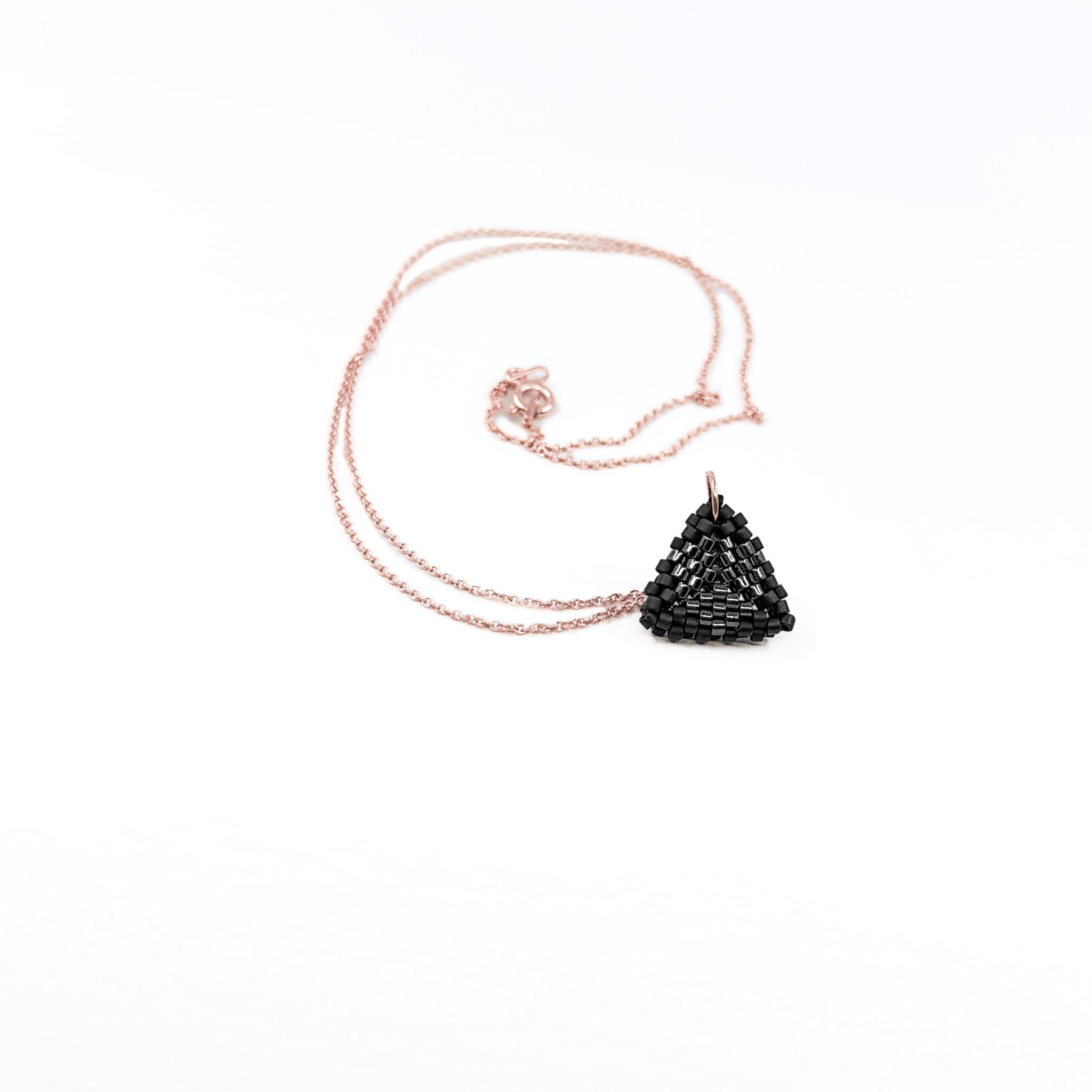 Black beaded triangle pendant on a rose gold chain with metallic center detail, charcoal black beads, front view.