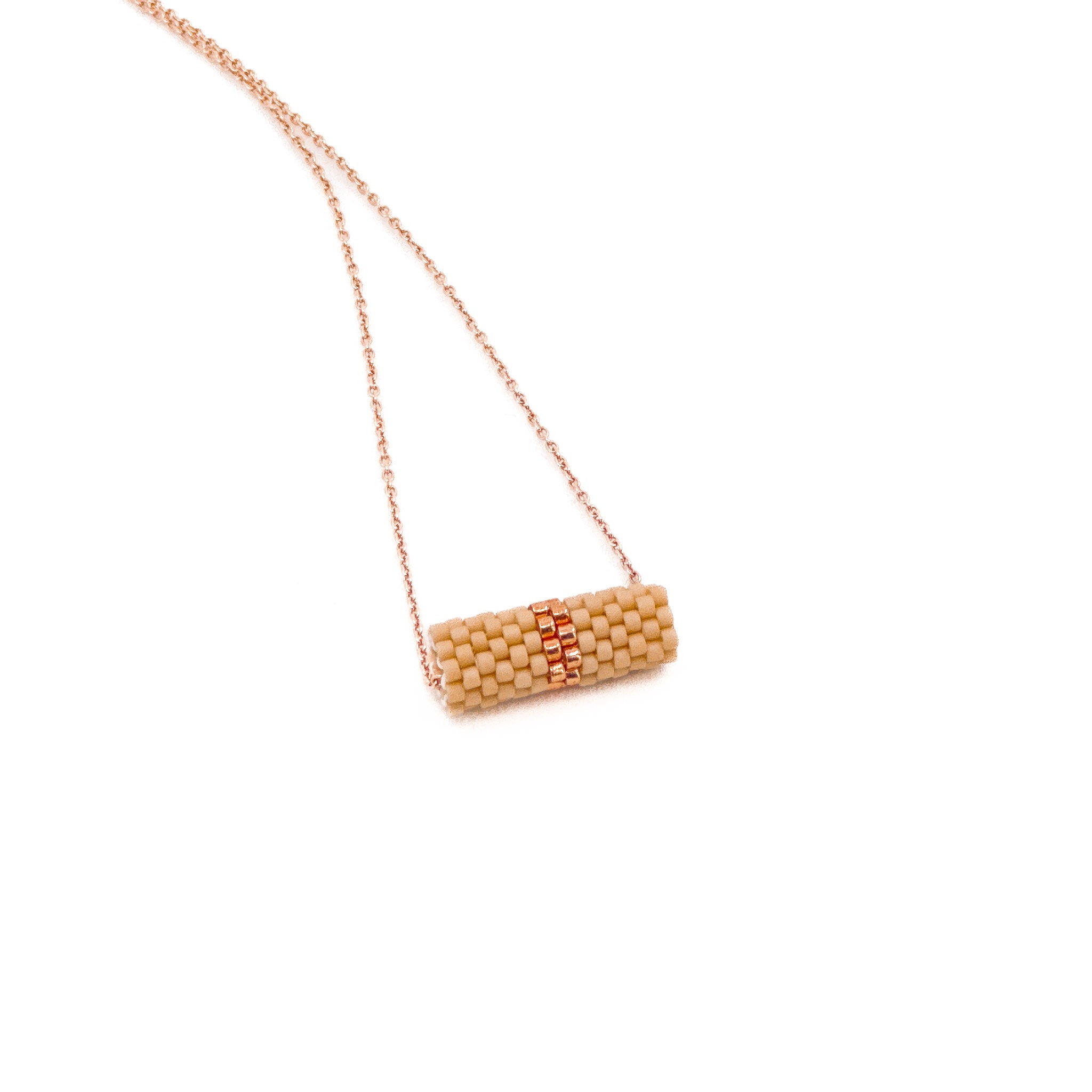 Beige beaded tube pendant necklace with rose gold chain and metallic center detail, rosy beige beads, side view.