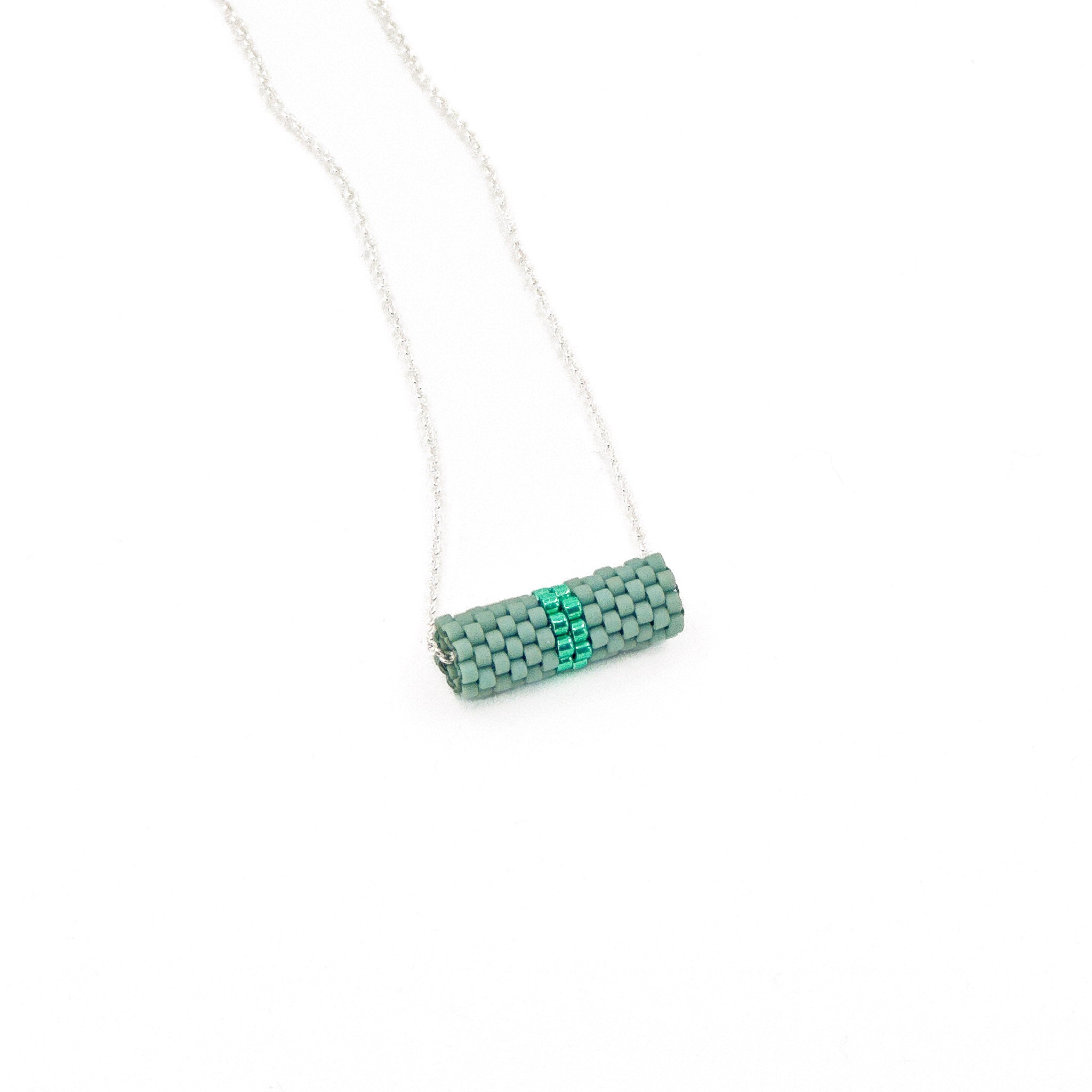 Green beaded tube pendant necklace with silver chain, sage green beads and bright emerald green center, side view.