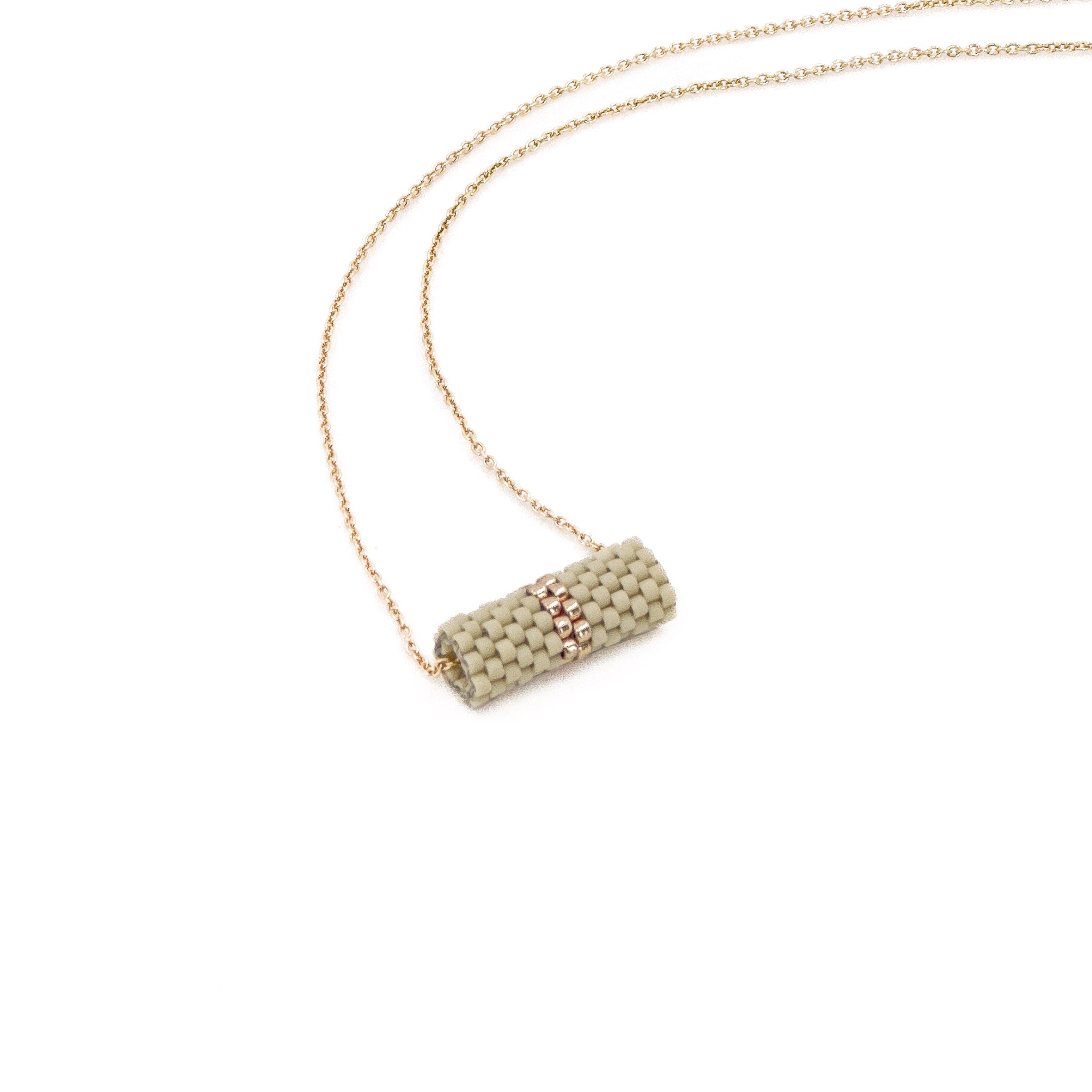 Greige beaded tube pendant necklace with gold chain and metallic center detail, beige gray tone beads, side view.