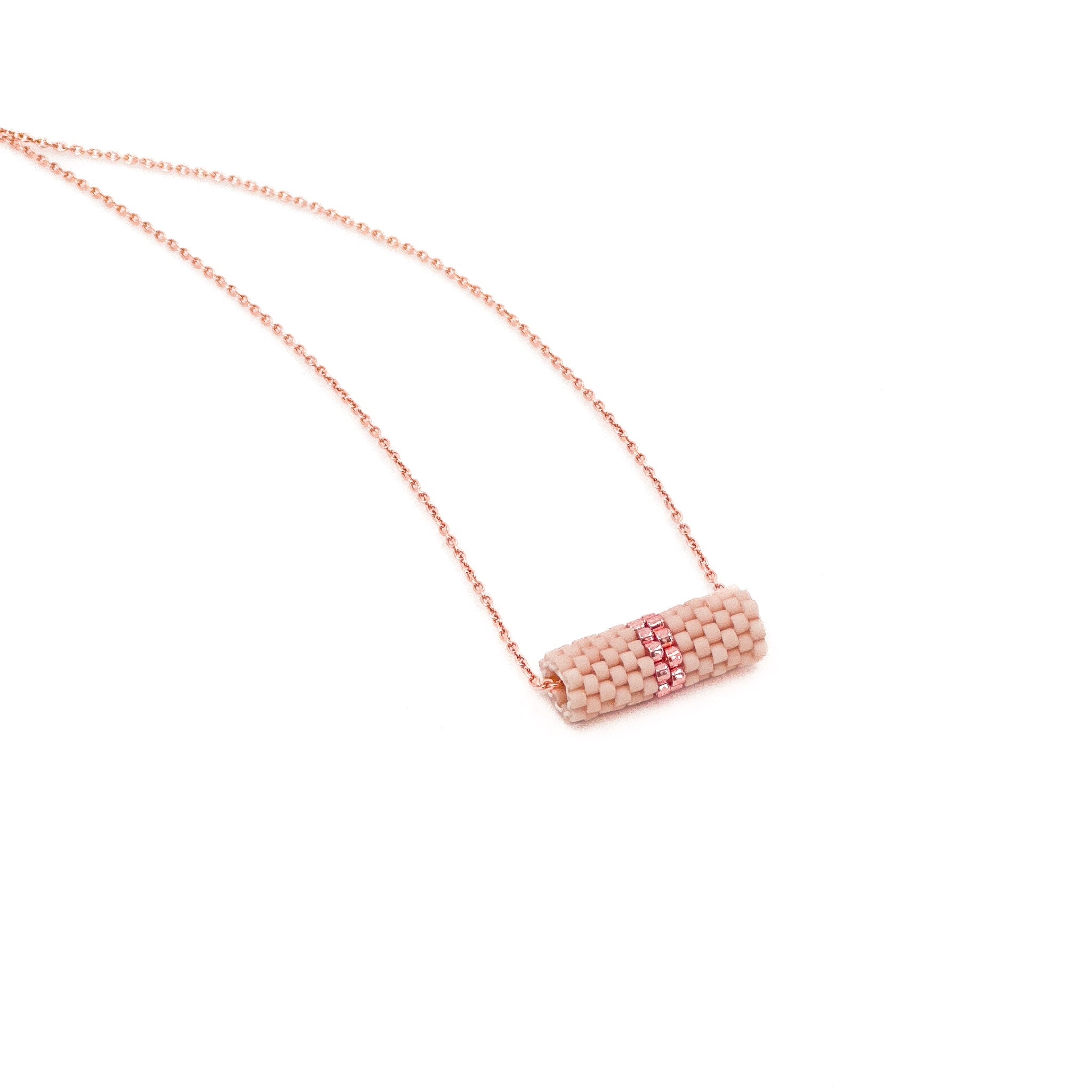 Pink beaded tube pendant necklace with rose gold chain and metallic center detail, blush pink beads, side view.